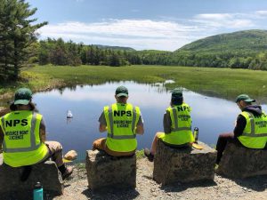 national parks service members outdoors with mountains in the background