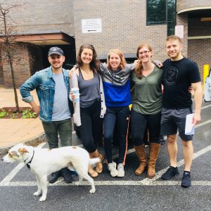 group of students standing outside of building with a dog