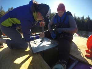 Two people measuring sediment on a raft platform